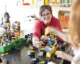 Maarit Piiparinen rakentaa lapsen kanssa legoilla iltapäiväkerhossa.