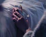 Läheinen ihminen pitää sairaalavuoteessa makaavaa potilasta kädestä.