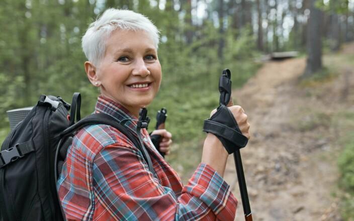 Vanhempi nainen sauvakävelemässä esteettömällä metsäpolulla.