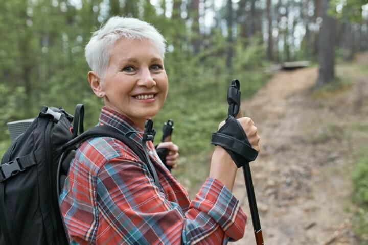 Vanhempi nainen sauvakävelemässä esteettömällä metsäpolulla.